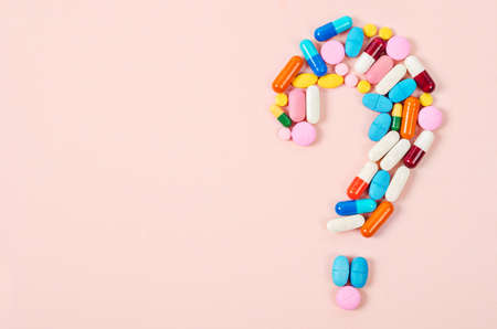 Question mark made of lots of pills and capsules on color background.の写真素材