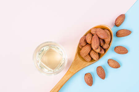 Peeled almonds seeds with almond oil on color paper background with empty space for your text or message.の写真素材