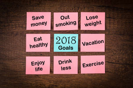 new year goals or resolutions 2018 with sticky notes on wooden background.