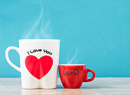 White and red cup hot coffee with smoke on wooden table and blue background. Love concept.の写真素材
