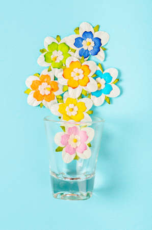 Romantic beautiful artificial colorful flowers with glass on blue background.の写真素材