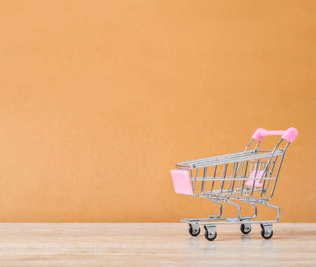 Beautiful pink shopping cart on wooden background with empty space for your text or message.の写真素材