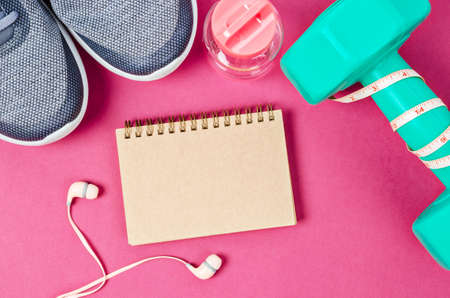 Blank notebook and dumbbell with sneakers on beautiful background, sport concept.の写真素材