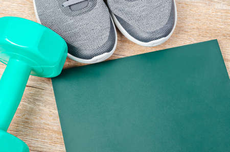 The sneakers, dumbbell with blank green board for your text or message on wooden background. Workout plan concept.の写真素材