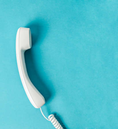 White office desk phone on blue with free space for your text or message.の写真素材