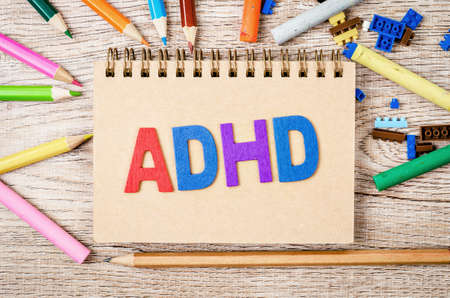 Attention Deficit Hyperactivity Disorder or ADHD concept with wooden pencil and against toys on woodenの写真素材