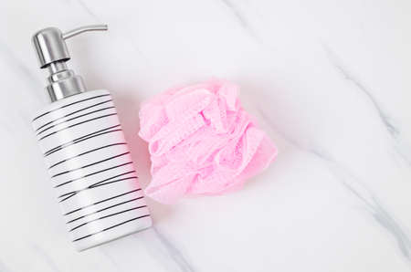 Sponge shower and ceramic pump bottle for liquid soap on marble background.