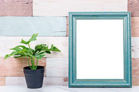 Blank vintage photo frame on wooden wall with plant, save clipping path.の写真素材