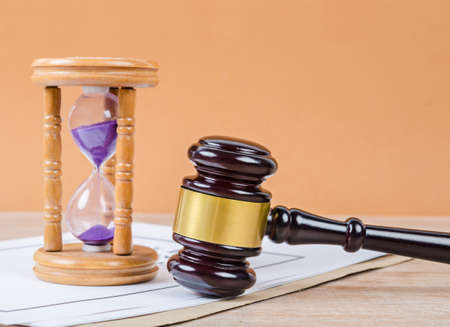 Judge's gavel with hourglass on the table background.