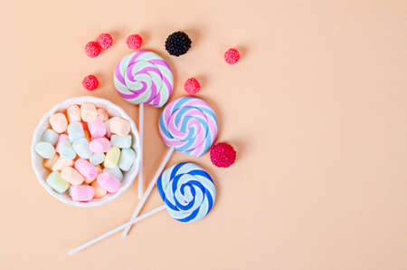 Colorful marshmallow in white cup and candies on pastel orangeの写真素材