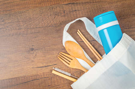 Zero waste concept. Textile eco bags, wooden glass and bamboo utensil on wooden background with copy space for text in center. Eco friendly and reuse concept. Top view or flat layの写真素材