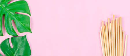 Wheat straw for drinking water and green leaves with empty space for your text or message on pink background. Zero waste concept.の写真素材