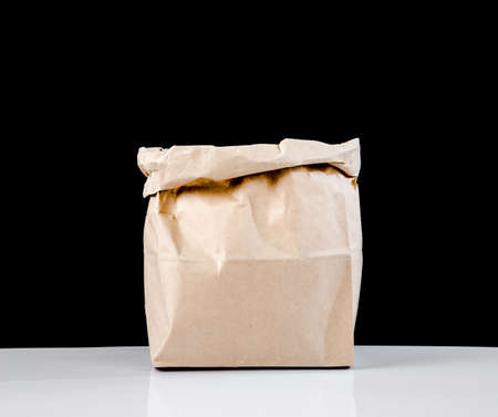 The empty open brown paper bag on black background.の写真素材