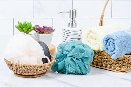Herb soap, shower sponge and shampoo pump bottle inside a bright bathroom background.の写真素材