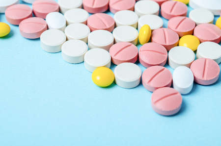 Many colorful pills macro on blue background.