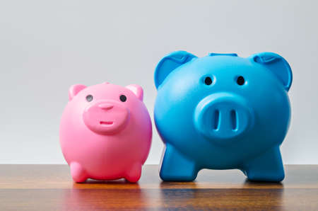 Pink and blue piggy bank on table background with empty space for your text or message.の写真素材