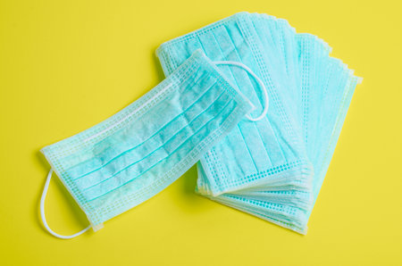 Medical disposable face mask on yellow background.