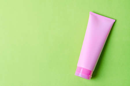 Empty a cosmetic pink tube of cream on green background with empty space for your text.の写真素材