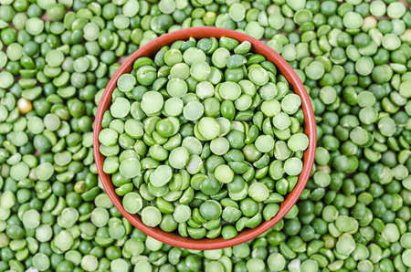 Green split peas in cup on split peas background.の写真素材