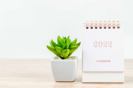 Mini desk calendar 2022 with cactus plant pot on wooden table.の写真素材