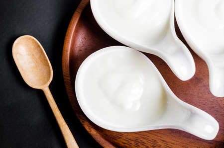 Greek yogurt in a white cup and dry barley on black background.の写真素材