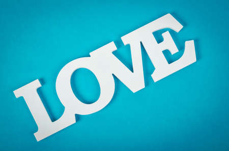 White wooden word love on blue background.