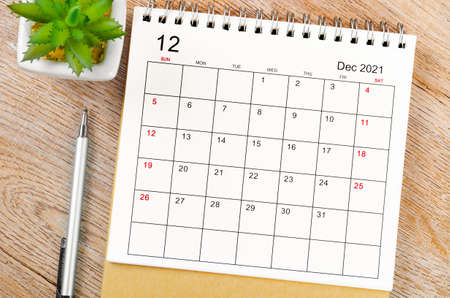 December 2021 desk calendar with pen on wooden table.
