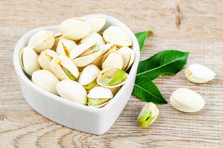 pistachio in shell nuts in bowl on wooden background.
