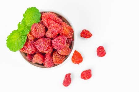 The dried sweet strawberries in cup with green leaves.
