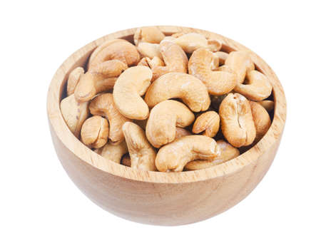 Big pile of cashew nuts in wooden bowl isolated on white backgroundの写真素材