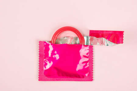 Pink opened condom unpack on a pink background. Safe sex and reproductive health concept.の写真素材