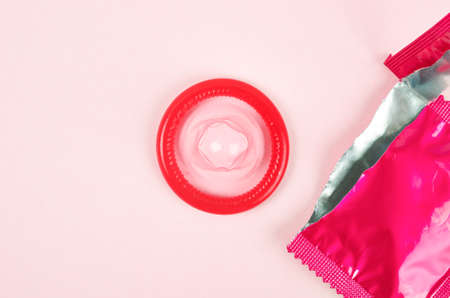 Pink opened condom unpack on a pink background. Safe sex and reproductive health concept.の写真素材