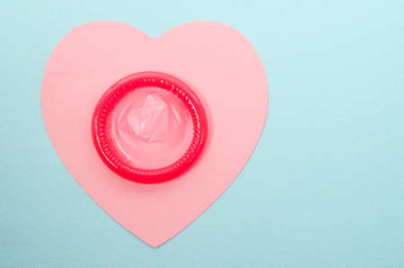 Pink condom unpackage on pink paper heart shape with copy space for your text or message.の写真素材