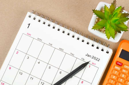 The January 2022 desk calendar with calculator on brown background.の写真素材