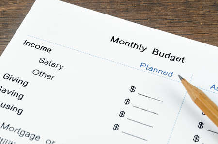 A print out of a monthly budget for your text with pencil on wooden background.の写真素材