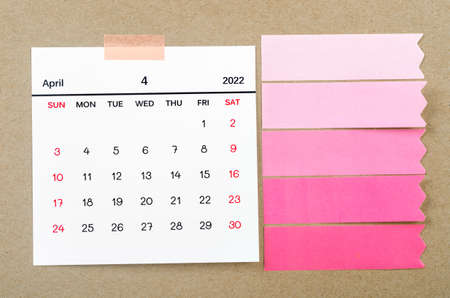 The April 2022 calendar with blank adhesive note paper on brown background.