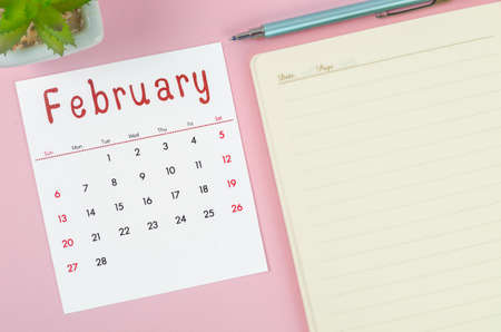 The February 2022 calendar with note book on pink background.の写真素材