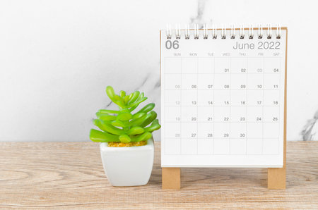 The June 2022 desk calendar with plant on wooden table.の写真素材