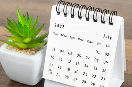 The July 2022 desk calendar with plant pot on wooden table.の写真素材