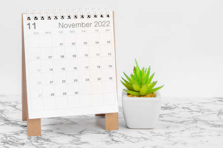 The November 2022 desk calendar with plant on marble table.の写真素材