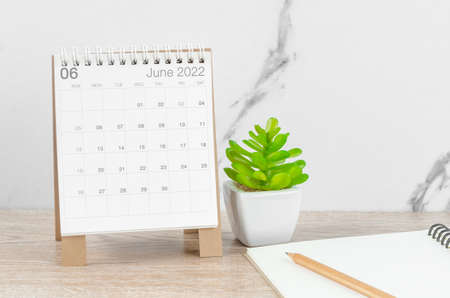 The June 2022 desk calendar with plant on wooden table.の写真素材