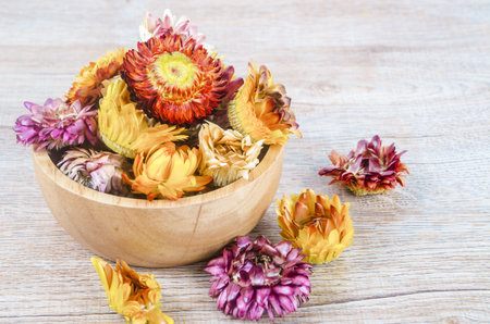 Dried straw flower heads in wooden cup on wooden background.の写真素材