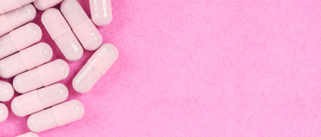 Pink capsule pills on pink background with copy space. Pharmacy web banner concepts.