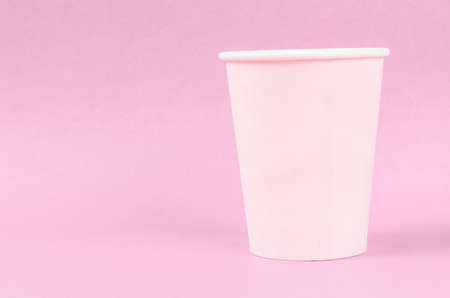Pink disposable paper cups on pink background with empty space.