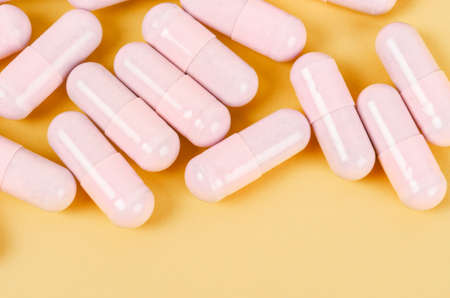 The Pink capsule pills on yellow background