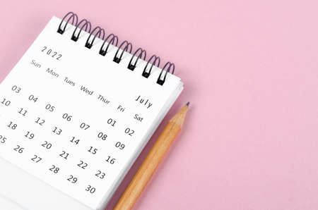 The July 2022 desk calendar with wooden pencil on pink background.の写真素材