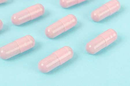 The Pink capsule pills on blue background.の写真素材
