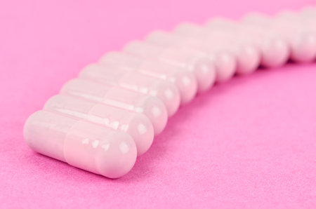The Pink capsule pills on pink background.