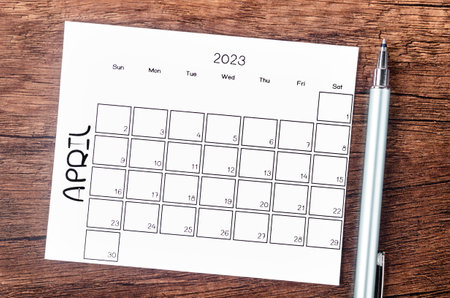 April 2023 Monthly calendar for 2023 year with pen on wooden table.