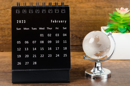 February 2023 desk calendar for 2023 year Black color with a crystal globe against a wooden table background.の写真素材